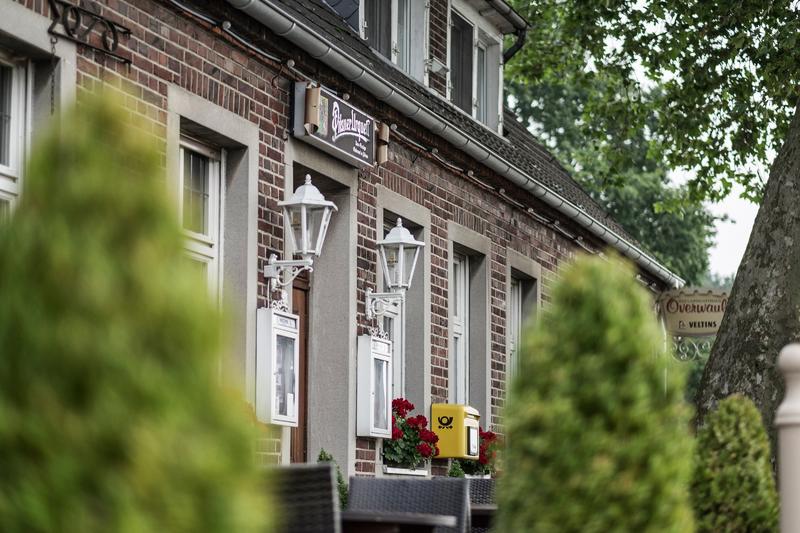 Backsteinfassade eines traditionellen Gebäudes mit weißen Fenstern und roten Blumen