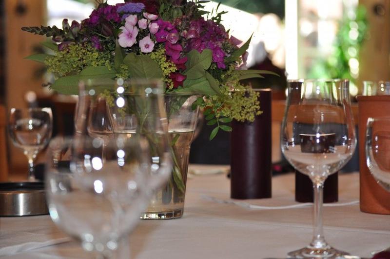 Ein stilvoll gedeckter Tisch mit lila Blumenstrauß und leeren Weingläsern