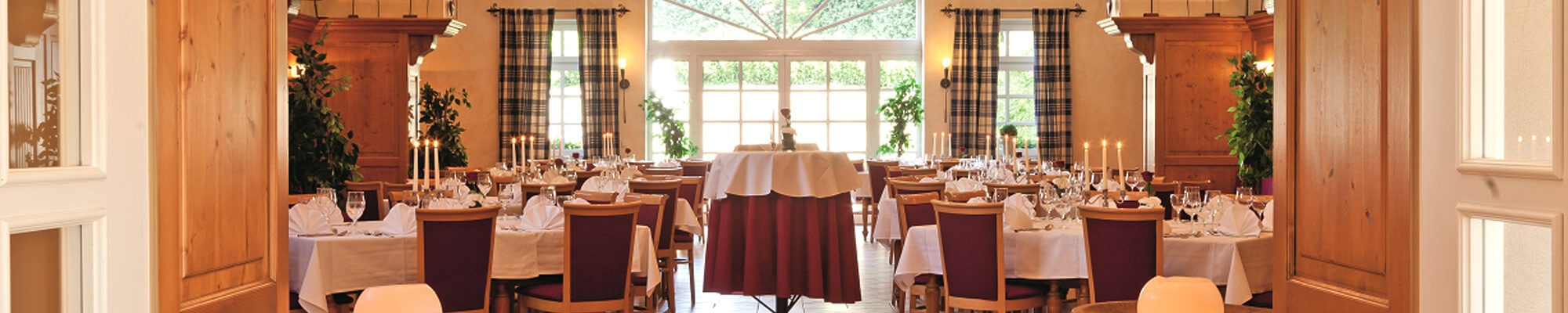 Helles elegantes Restaurant mit weiß gedeckten Tischen und Kerzen auf Holzmöbeln
