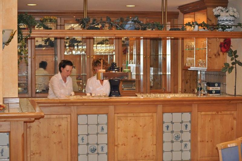 Zwei Personen mit weißer Kleidung arbeiten freundlich hinter einer rustikalen Holztheke