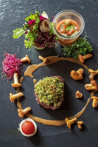Ein kunstvoll angerichtetes grünes Steak mit Pilzen, Salat und Tomatensauce