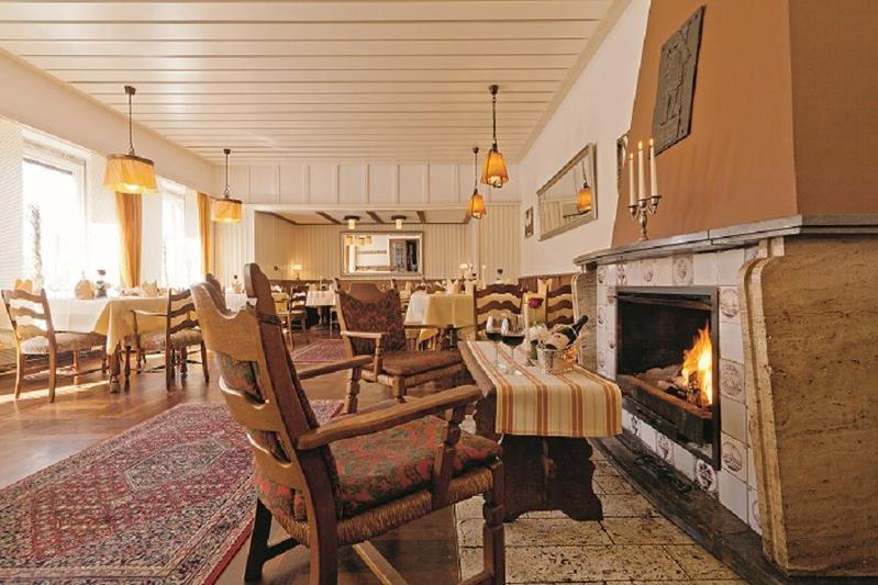 Gemütliches Restaurant mit brennendem Kamin, Holzmöbeln und warmen Farbtönen