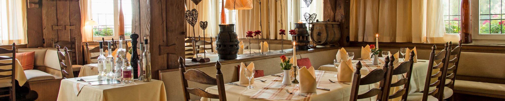 Helles Restaurant mit Holzstühlen, dekorativen Kerzen und liebevoll gedeckten Tischen