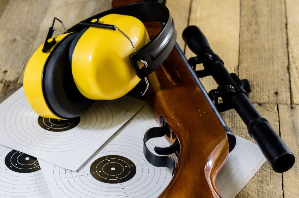 Schießen, Druckluft- und Schusswaffen auf einem Holztisch. Tisch auf dem Schießstand, Waffen und Schießzubehör.